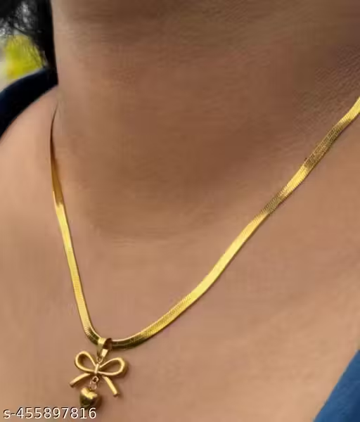 Gold-tone bow and heart pendant necklace held in hand