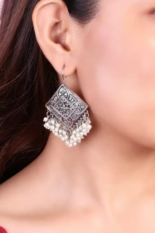 Geometric oxidised silver-tone pearl tassel earrings worn on ear