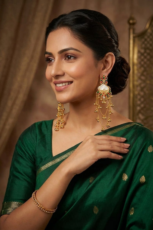 White red and green traditional long jhumka earrings displayed on a dark wood background