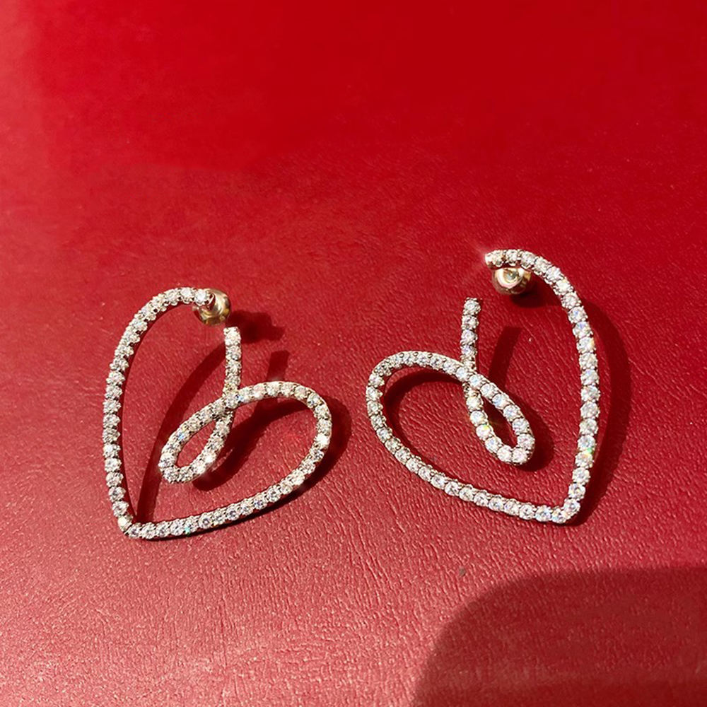 Crystal-pave heart earrings close-up on hand