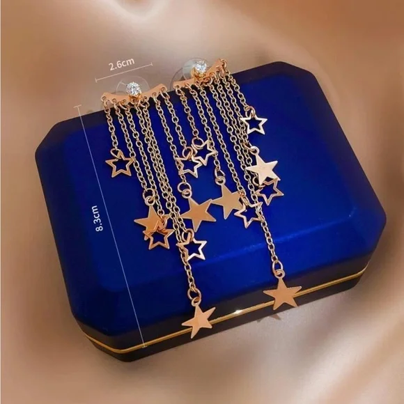 Gold-tone star chain earrings worn on ear