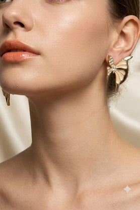 Gold-tone butterfly earrings with crystal detailing worn on ear