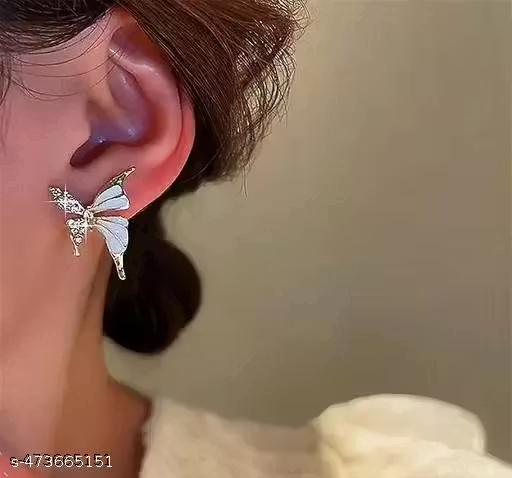 White and gold-tone butterfly earrings worn on ear